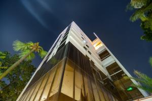 达卡Emerald Dhaka Luxury Hotel的一座高大的建筑,前面有一棵棕榈树