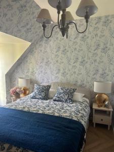 a bedroom with a blue bed with blue floral wallpaper at Agnes Little Corner in Honfleur