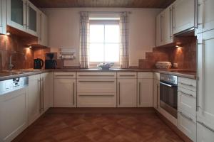 a kitchen with white cabinets and a window at Ferienhaus Am Riedl in Siegsdorf