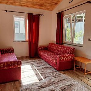 un soggiorno con divano rosso e finestre di OLYMPOS YÖRÜK OTAĞI APART EVLERİ a Kumluca