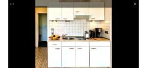 a kitchen with white cabinets and a sink at FeWo Usedom Karlshagen in Karlshagen