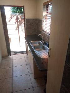 a small kitchen with a sink and a window at Schubert Self Catering Accomodation in Brackenfell