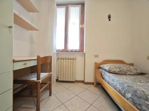 a bedroom with a bed and a desk and a window at Terrazza Su Crosio a Clusone in centro! in Clusone
