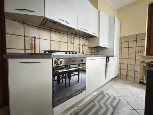 Una cocina con gabinetes blancos y una mesa. en Terrazza Su Crosio a Clusone in centro!, en Clusone