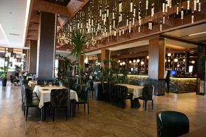 un ristorante con tavoli, sedie e un lampadario di Iliria Hill Resort & Spa a Orllan