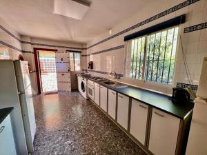 a large kitchen with a sink and a refrigerator at Villa Marietta, private pool villa with sea views and terrace, perfect for families and remote stays in Almuñécar