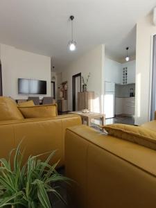 a living room with yellow couches and a kitchen at Cozy apartment Lalez in Shetaj +42 photos
