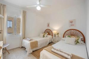 a white bedroom with two beds and a table at Next to piletas 67 Sanlucar de Barrameda in Sanlúcar de Barrameda