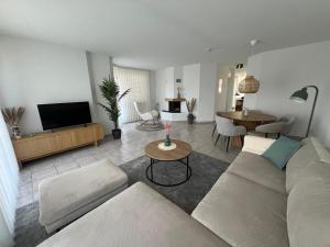 a living room with a couch and a tv and a table at Casa Tricolina - Lake Life am Bielersee 