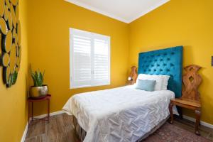 a bedroom with a bed with a blue headboard and a window at Affordable Luxury in Cape Town