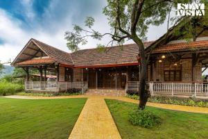 a building with a tree in front of it at StayVista at Orchard by the River with Bonfire, BBQ in Karjat