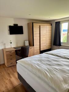 a bedroom with a bed and a desk and a television at suite4you Erlen in Erlen