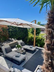 a patio with two chairs and an umbrella at Suite4you Erlen l Privater Indoorpool ganzjährig beheizt & Sauna l 10min zum Bodensee, Parkplatz & WLAN in Erlen