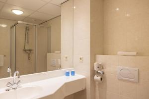 une salle de bain avec un lavabo et un miroir dans l'établissement Fletcher Hotel - Restaurant de Cooghen, à De Koog 45 autres photos