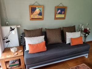 a couch in a living room with orange and white pillows at KNUS tiny gardenhouse in Doorn
