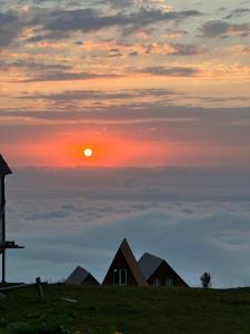 a sunset over a field with houses on a hill at Gomismta Panorama in Gomi +10 photos