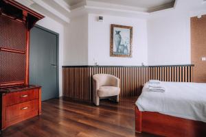 a bedroom with a bed and a chair and a dresser at District&Villa De Lago in Ohrid