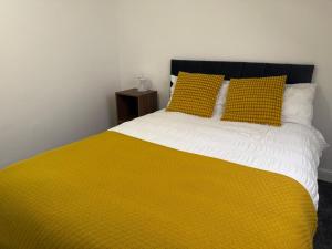 a bed with a yellow blanket and two yellow pillows at Nice Room 6 in Avonmouth