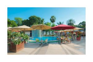 una piscina con mesas, sillas y sombrillas en Andy's Boutique Hotel, en Bombay