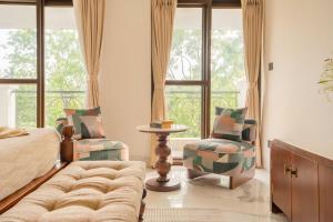 een slaapkamer met een bed en een bank en stoelen bij Casa Verdea 4-BHK Villa With Private Pool & Lift Near Popular Restaurants in Siolim