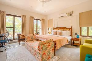 een hotelkamer met een bed, een bank en ramen bij Casa Verdea 4-BHK Villa With Private Pool & Lift Near Popular Restaurants in Siolim
