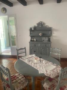 a dining room with a table and chairs and a dresser at LE Doux Nid La Classique in Saint-Aulaye