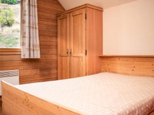 ein Schlafzimmer mit einem Bett und einem Holzschrank in der Unterkunft Charmant Chalet 6 Pers. avec Terrasse et Parking - Résidence Les Chalets de Praroustan, Pra Loup 1500 - FR-1-504-364 in Uvernet