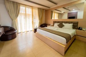 une chambre avec un grand lit et une chaise dans l'établissement Grandeur De Sanchi Resort, à Calangute