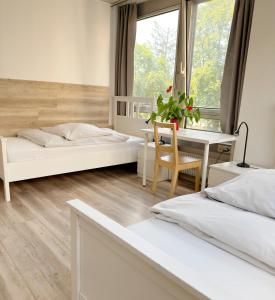 een slaapkamer met twee bedden, een bureau en een tafel bij Sprachcaffe Appartements in Frankfurt am Main