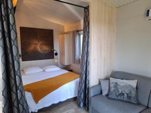 a bedroom with a bed and a chair in a room at Les Cabanes d'Isa - Cab'Fer in Flexanville