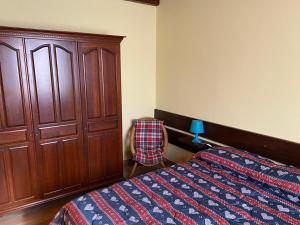 a bedroom with a bed and a cabinet and a chair at Cottage Etna nel Cuore in Nicolosi