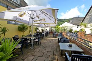 eine Terrasse mit Tischen, Stühlen und einem Sonnenschirm in der Unterkunft Landgasthof Zur Sonne in Enkirch