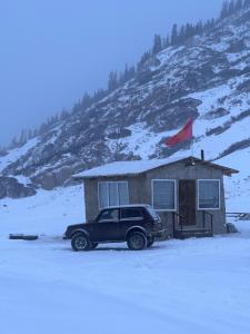 a car parked in front of a house in the snow at Shatyly Camp in Tong +5 photos