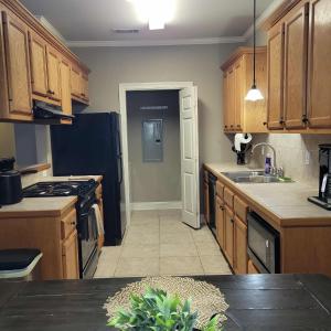 a kitchen with wooden cabinets and a black refrigerator at LSU Den in Baton Rouge +12 photos