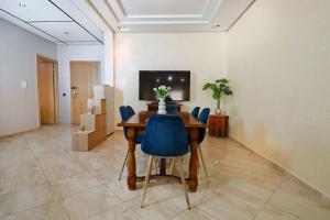 盖尼特拉Le Cosy Appartement 3 chambres au coeur de Kenitra的一间带桌子和蓝色椅子的用餐室