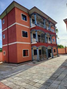 a large red building with balconies on top of it at Air-conditioned apartment, secured Residence Kribi in Kribi