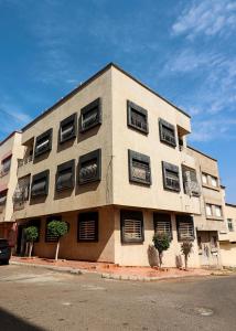 盖尼特拉Le Cosy Appartement 3 chambres au coeur de Kenitra的街道上设有黑色百叶窗的建筑