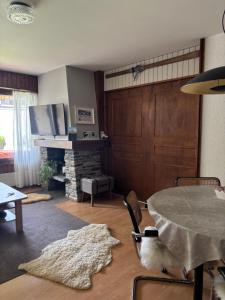 a living room with a table and a fireplace at Charmant appartement, hyper central, à 2 min de tout, énorme terrasse privée et parking couvert in Crans-Montana