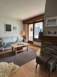 a living room with a couch and a table at Charmant appartement, hyper central, à 2 min de tout, énorme terrasse privée et parking couvert in Crans-Montana