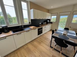 a kitchen with white cabinets and a table with chairs at Villa Jeanne in Saint-Nazaire-en-Royans