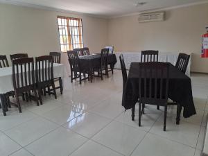 a dining room with black tables and chairs at Palmetto guesthouse in Mahikeng