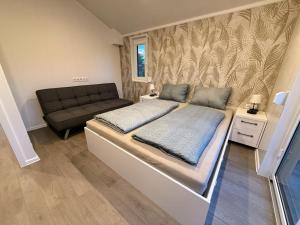 a bed in a small room with a couch at TRB - Tiny Room Bodensee 2 in Gaißau