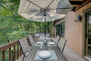 Una mesa de madera con una sombrilla en una terraza. en 4 BR Lakeside House in Woods, en Analomink