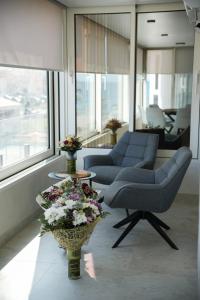 a living room with two chairs and a table with flowers at Sucro Playa Apartment in Cullera