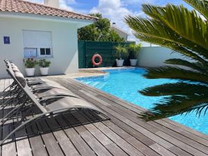 a swimming pool with a wooden deck next to a house at Casa Magnolia B&B in Gafanha da Nazaré