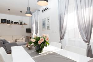 a white dining room with a vase of flowers on a table at Split Center brand new Apartment Jazzy in Split