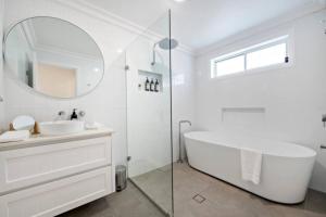 a bathroom with a tub and a sink and a mirror at Macintyre House in Dubbo +13 photos
