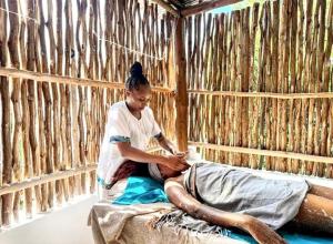 a woman sitting on a bed in a hut at Blue Diamond Villa Watamu in Watamu