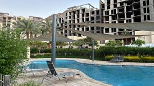 a swimming pool with two chairs and umbrellas at Flow - Al Raha Village in Aqaba +1 photo