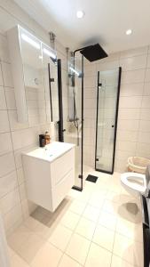 Un baño blanco con lavabo y ducha. en Modern apartment in the heart of Drammen, en Drammen